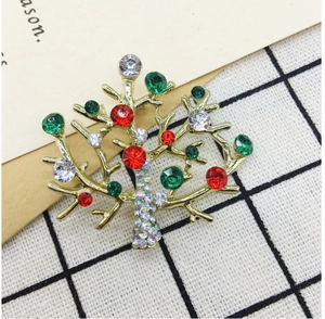 Detailed close-up of a Christmas tree brooch with red and green rhinestones on gold metal