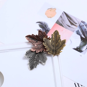 Macro shot of maple leaf brooches in bronze, silver and gold metal showing fine textures