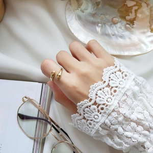 Detailed view of an adjustable gold hugging hands ring worn on a finger in a vintage setting