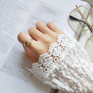 Detail of a golden hug-shaped ring on a finger with an elegant lace cuff and book background