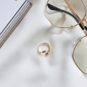 Close-up of golden hug-shaped open ring featuring hands embracing design on silk fabric