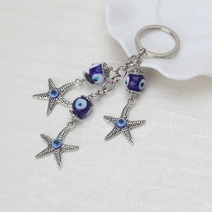 Detailed macro view of silver starfish charms and blue evil eye beads on a key chain
