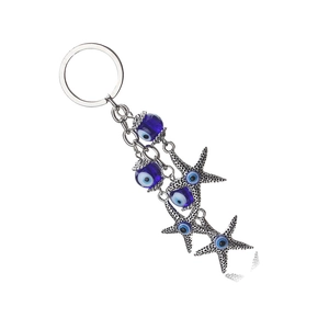 Detailed shot of evil eye glass bead and silver starfish charm on a metal keychain