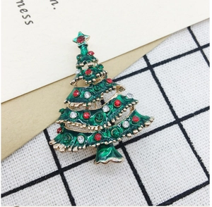Close-up of green Christmas tree brooch with red rhinestones on plaid fabric