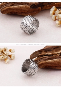 Detail of silver hollow-out ring with sparkling white zircons and wavy edges on wood