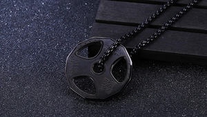 Close-up of black metal fitness weight plate pendant with Live Fit engraving on chain