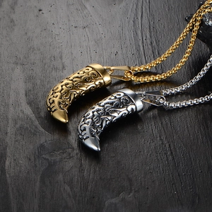 Dettaglio macro dei ciondoli a dente di lupo in oro e argento con incisioni vintage