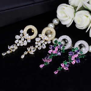 Detailed view of floral zircon drop earrings in gold and multicolor on black background