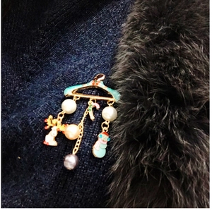 Detailed view of Christmas coat hanger brooch with enamel charms on dark knitwear