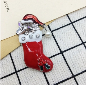 Macro shot of red cat stocking brooch with enamel finish, crystals, and a hanging pearl