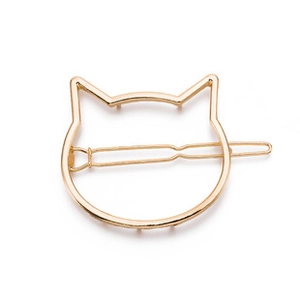 Detailed close-up of golden hollow cat head metal hair clip on white background