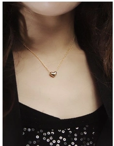 Close-up of elegant gold heart pendant necklace on female model neck
