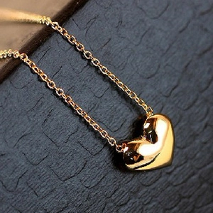 Close-up of a polished 3D heart pendant on a delicate gold-toned necklace chain