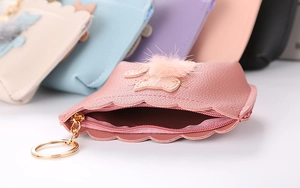 Close-up of pink PU leather coin purse with cute cat pattern, fur ball, and metal zipper