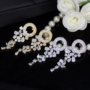 Close-up of gold and silver wreath earrings with AAA zircons on a black surface
