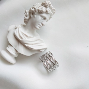 Macro shot of layered criss-cross silver ring with crystal accents on white silk