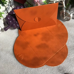 Macro detail of orange pearlescent envelope with heart-shaped buckle in folded view