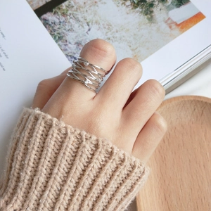 Close-up of S925 silver layered crisscross ring with white zircons on a thumb