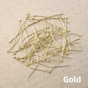Macro shot of gold-plated metal ball pins for DIY jewelry making and bead craft projects