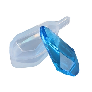 Vue macro du moule en silicone de prisme et pendentif en résine bleue sur fond blanc