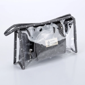 Three-piece clear PVC and grey polka dot travel makeup bag set on white background