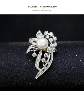 Macro shot of a floral silver brooch with a large white pearl and sparkling rhinestones