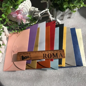 Fanned out pearlescent heart-buckle envelopes in various vibrant colors with wooden ruler