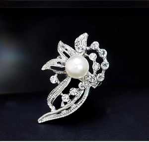 Macro shot of silver floral brooch with white pearl and sparkling rhinestones