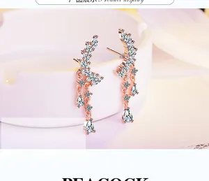 Detail of rose gold feather earrings with cubic zirconia and long tassel pendants