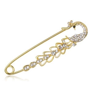 Detailed macro view of golden peacock brooch with white crystals and safety pin closure