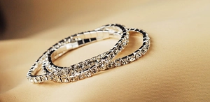Close-up of three interlocking silver elastic bracelets with full crystal rhinestones
