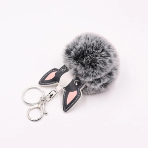 Close-up of a grey plush ball keychain with a cartoon bulldog PU leather charm