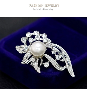 Macro detail of elegant silver flower brooch with white pearl and sparkling rhinestones