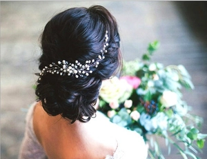 Silver bridal hair vine with pearls and crystals shown on bride's elegant hairstyle