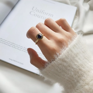 Detail of S925 silver gold ring with deep blue sapphire on model hand against white background