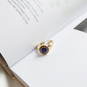 Detail of S925 sterling silver ring with blue stone on an open book, minimalist aesthetic