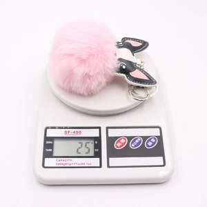 Pink plush pom pom keychain with puppy leather charm on a digital scale weighing 25g