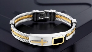 Close-up of men's two-tone braided steel cable bracelet featuring a gold cross accent