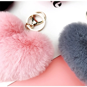 Close-up of heart-shaped faux fur keychains in pink and grey with gold metal hardware