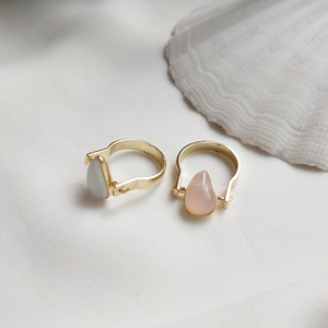 Detailed shot of gold-plated 925 silver rings with teardrop pearls on white silk fabric