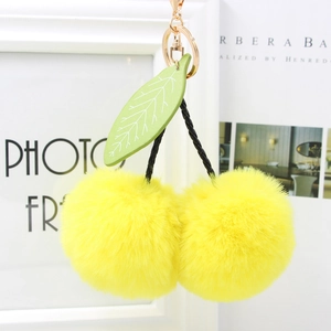 Detailed shot of yellow cherry plush keychain with green leaf and golden metal clasp