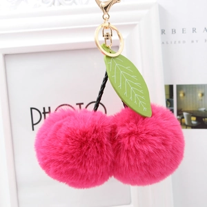 Detail of bright pink faux fur cherry keychain with green leather leaves and gold clasp