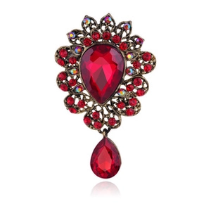 Close-up of vintage bronze rose brooch with red crystal teardrop pendant and stones