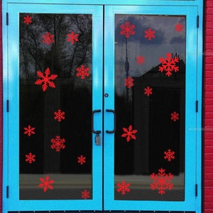 Christmas window stickers featuring various red snowflake designs on a glass door