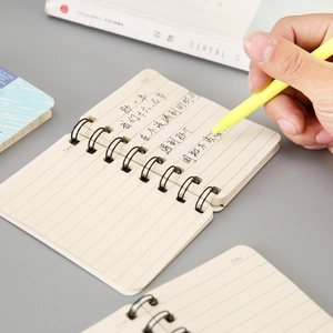 Close-up of A7 spiral notebook with creamy lined paper and a yellow gel pen