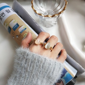 Detail of teardrop cat eye stone rings in pink and white with adjustable gold bands