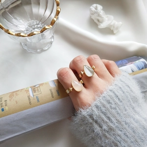 Close-up of elegant gold pear-cut rings with opal and rose quartz stones on hand