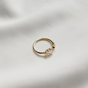 Detail of gold-plated silver ring with oval white stone and small red gemstone accent