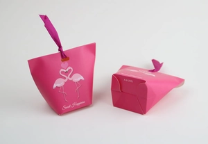 Macro detail of flamingo candy box with Sweet Happiness text and purple satin ribbon
