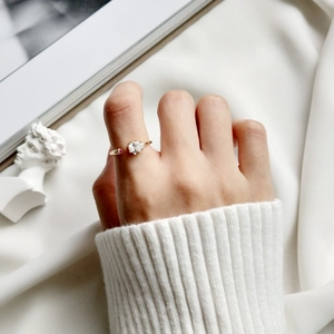 Close-up of golden S925 silver ring with teardrop zircon on a finger in cozy knitwear